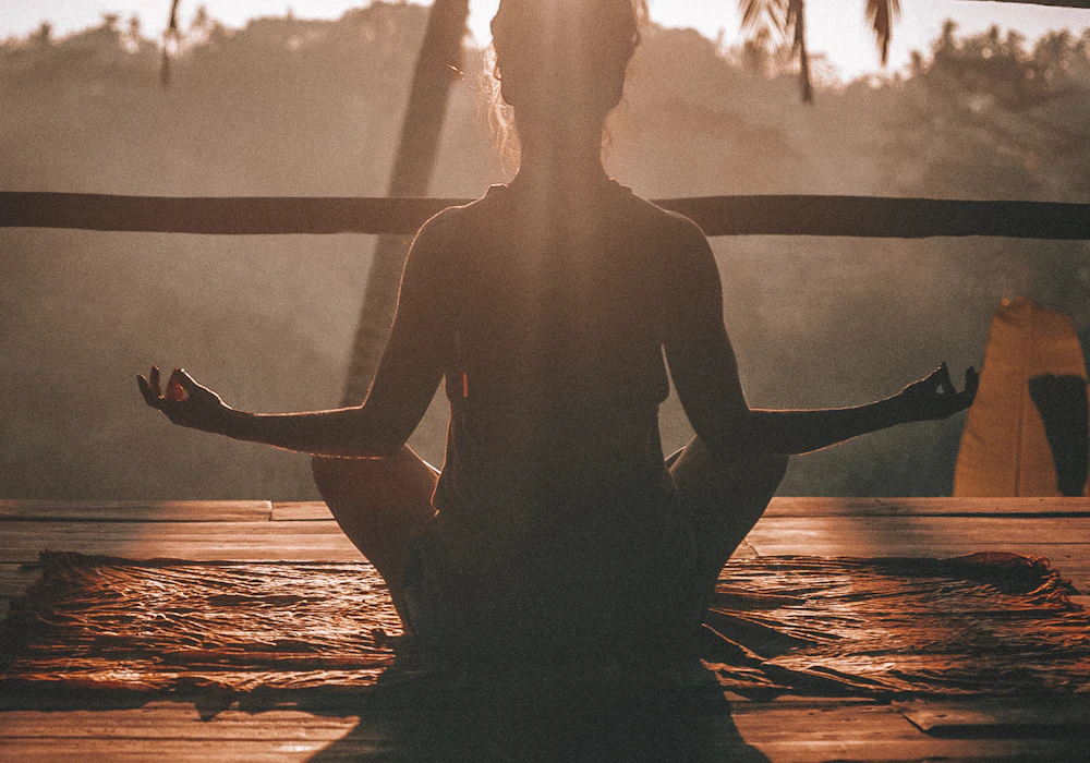 Person seated in a calm pose in warm morning light